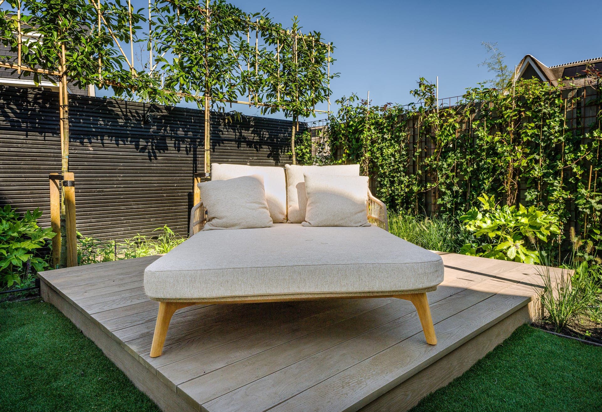 Houten vlonder met daybed omringd door leibomen