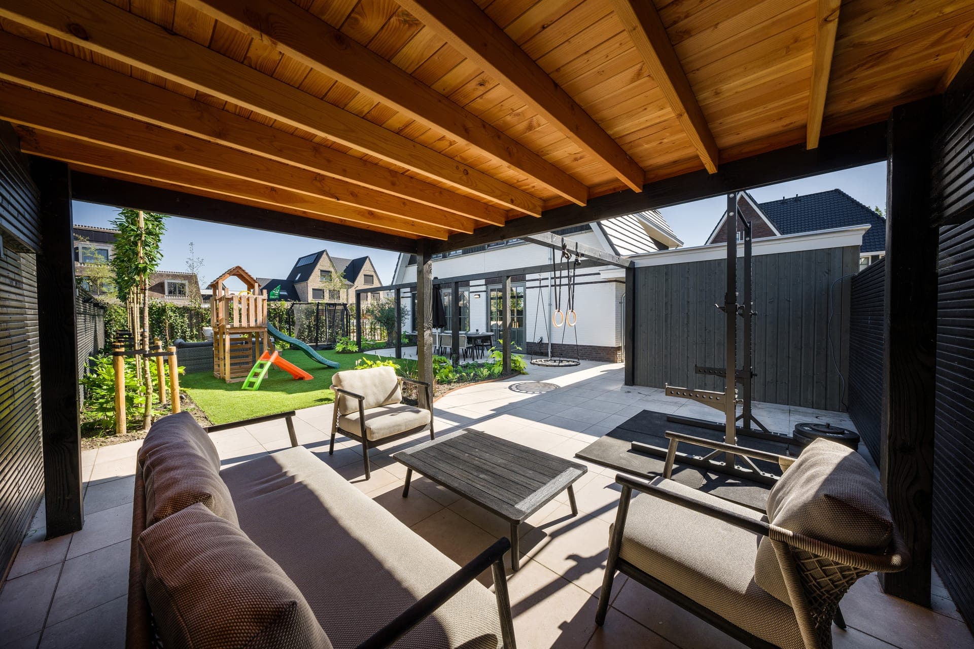 Overkapping met loungeset en uitzicht op de speeltuin