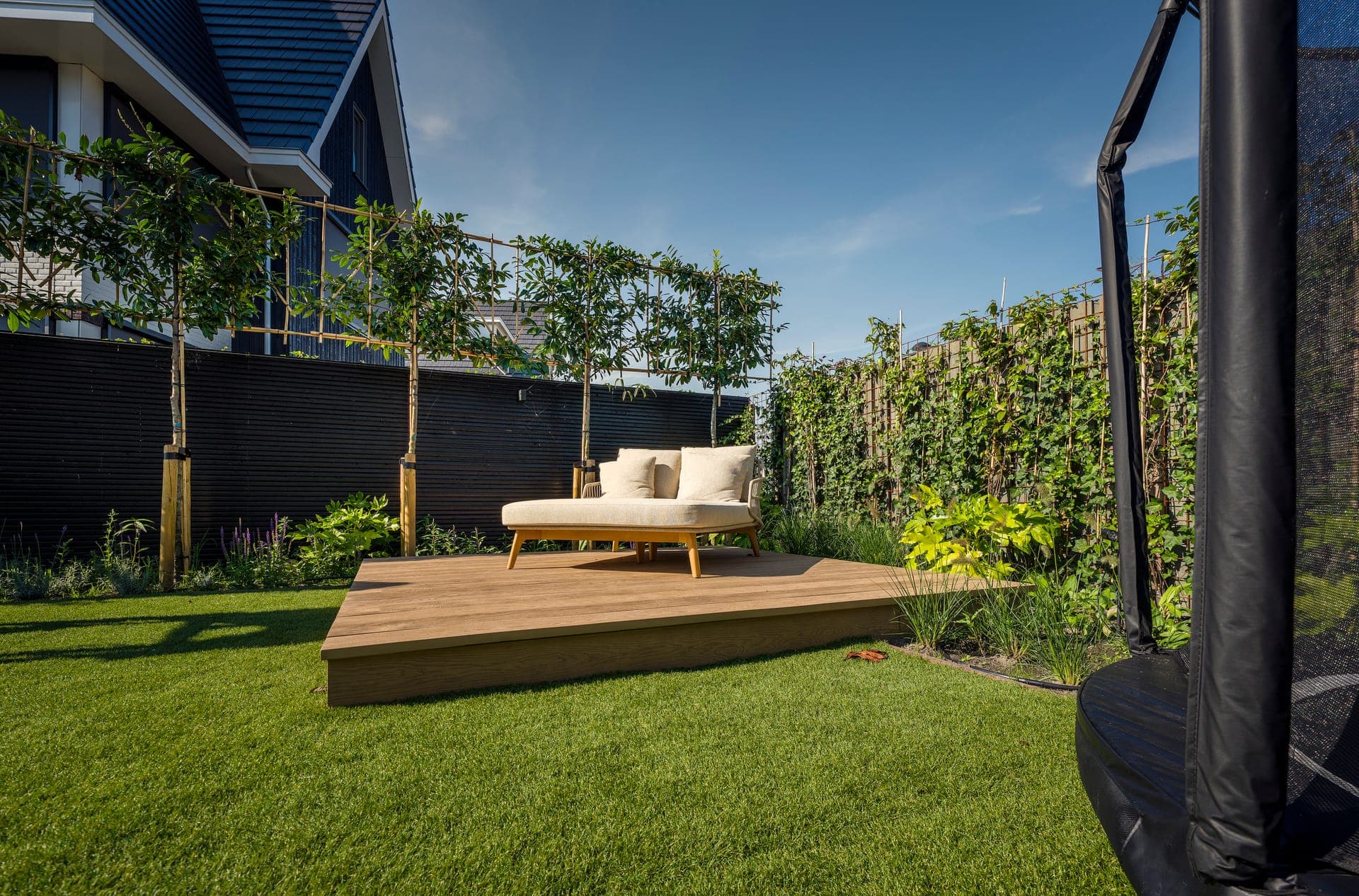 Daybed op het platform met leibomen en trampoline