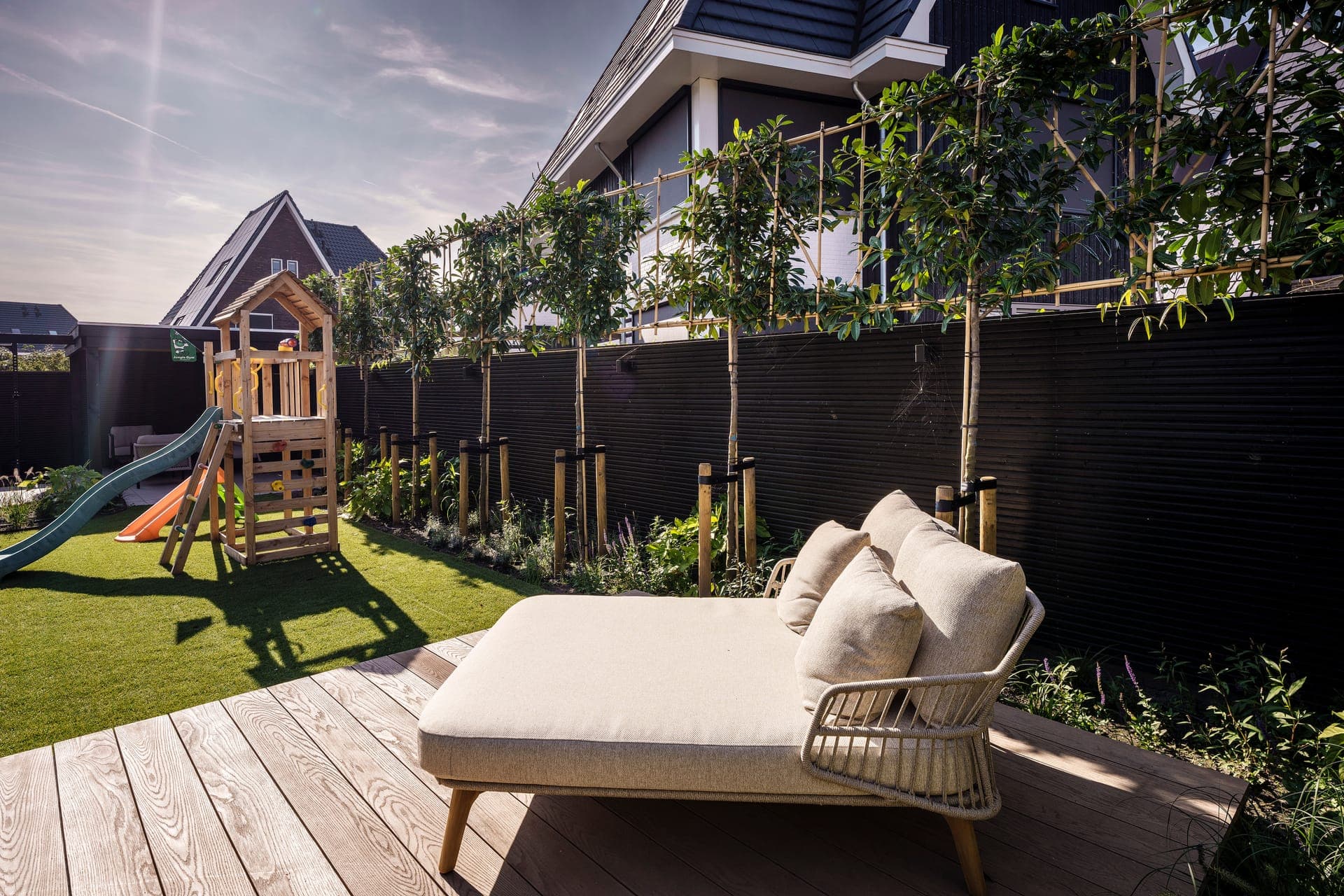 Daybed op de vlonder met speelhuis op de achtergrond