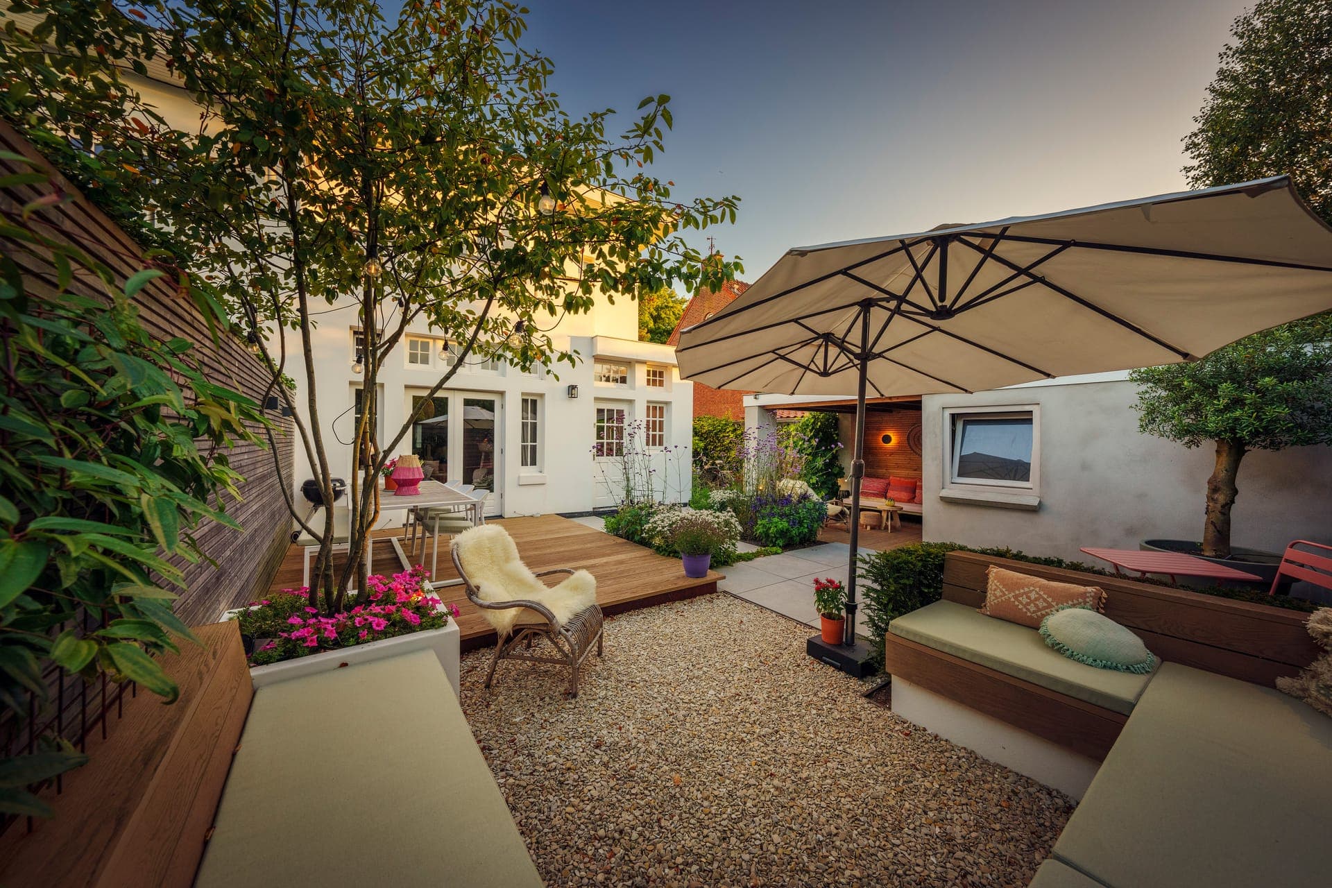 Overzicht van het grindterras met parasols en tuinhuis