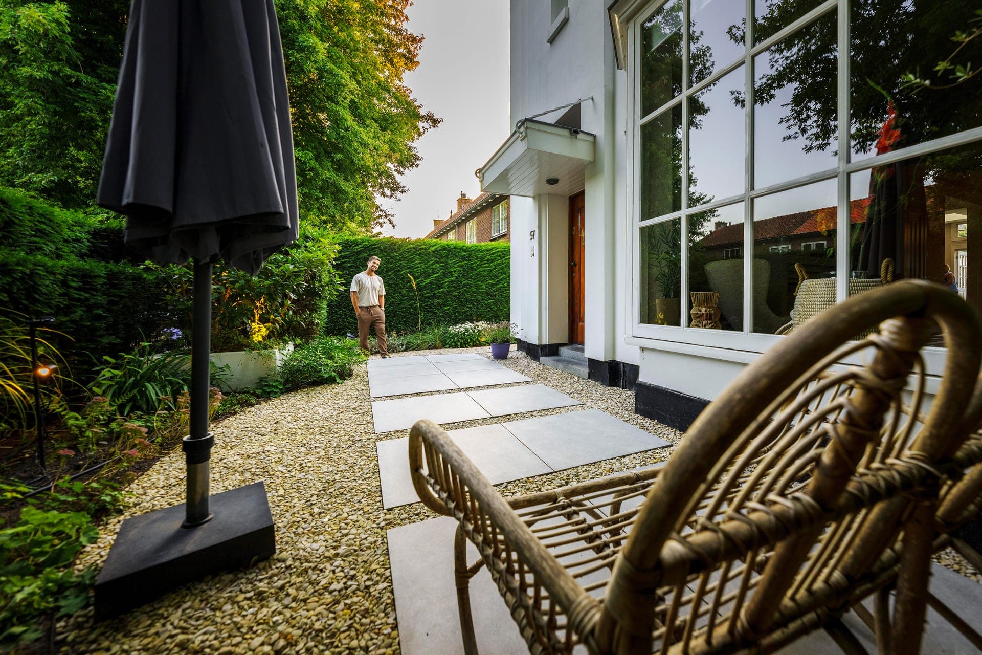 Zijpad met grote tegels in grind langs de witte woning