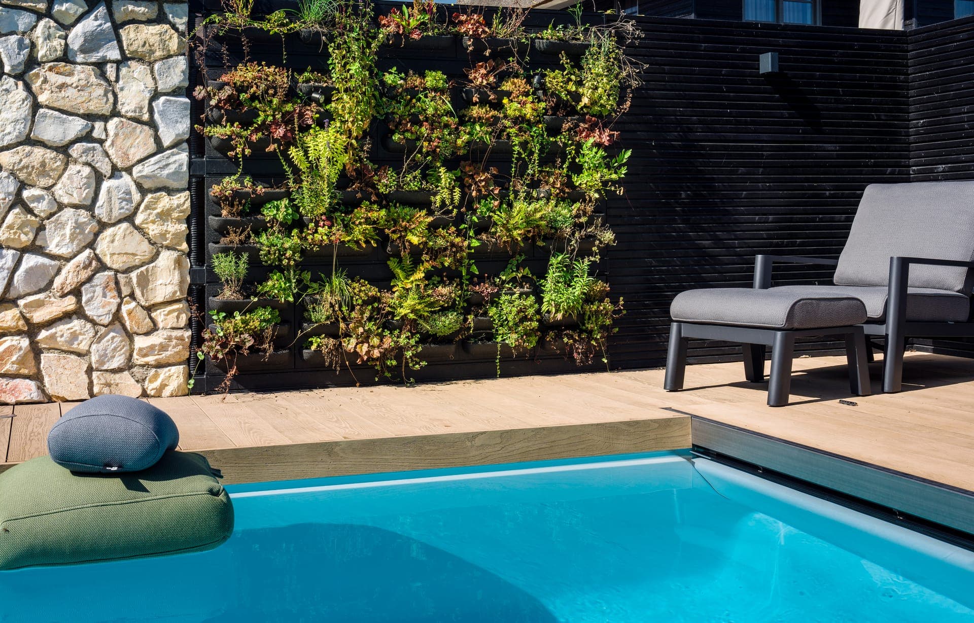 Verticale groene wand naast het zwembad met loungestoel