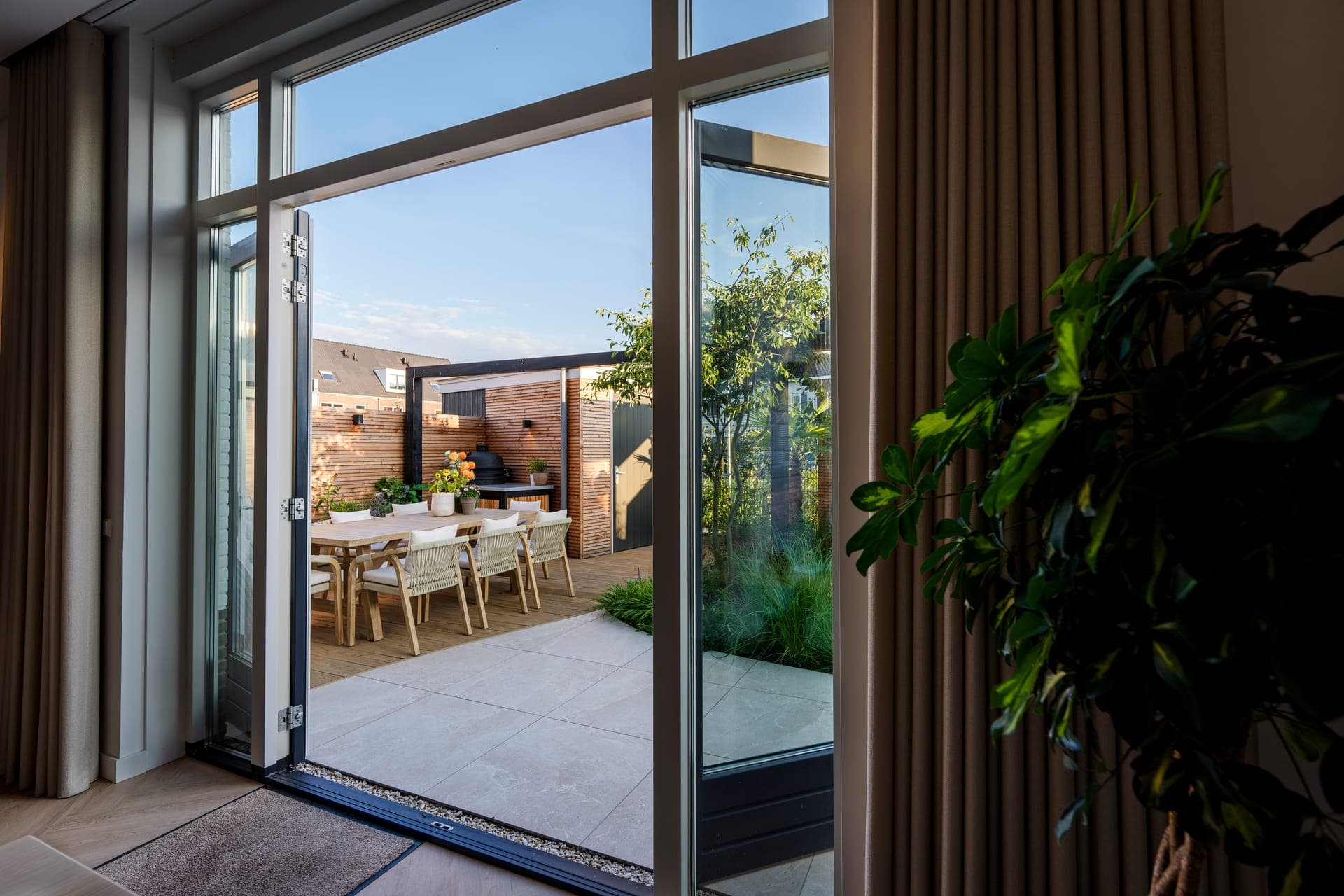 Doorkijk vanuit het interieur naar eettafel en buitenkeuken