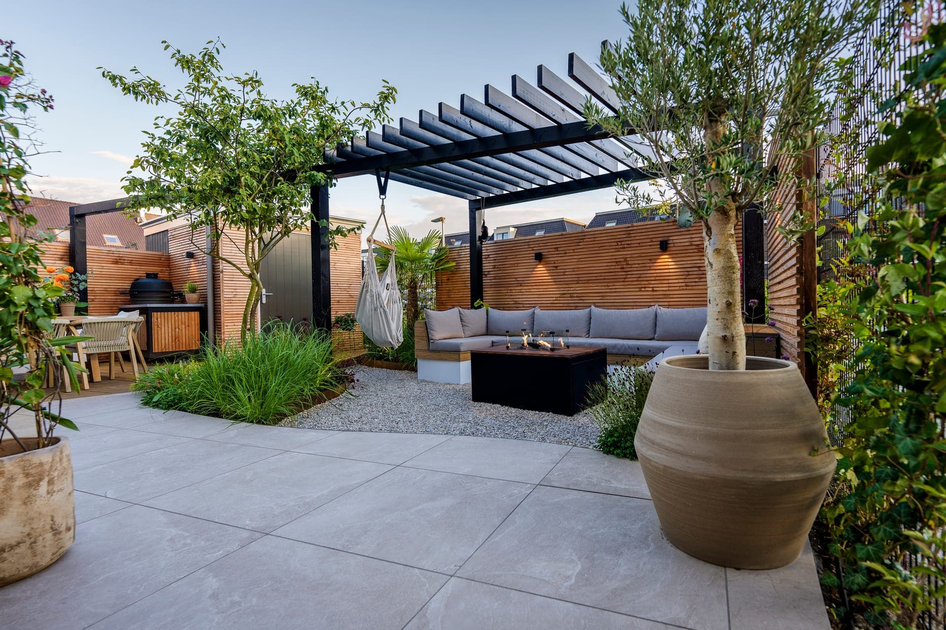 Terras met pergola, vuurtafel en olijfboom in pot