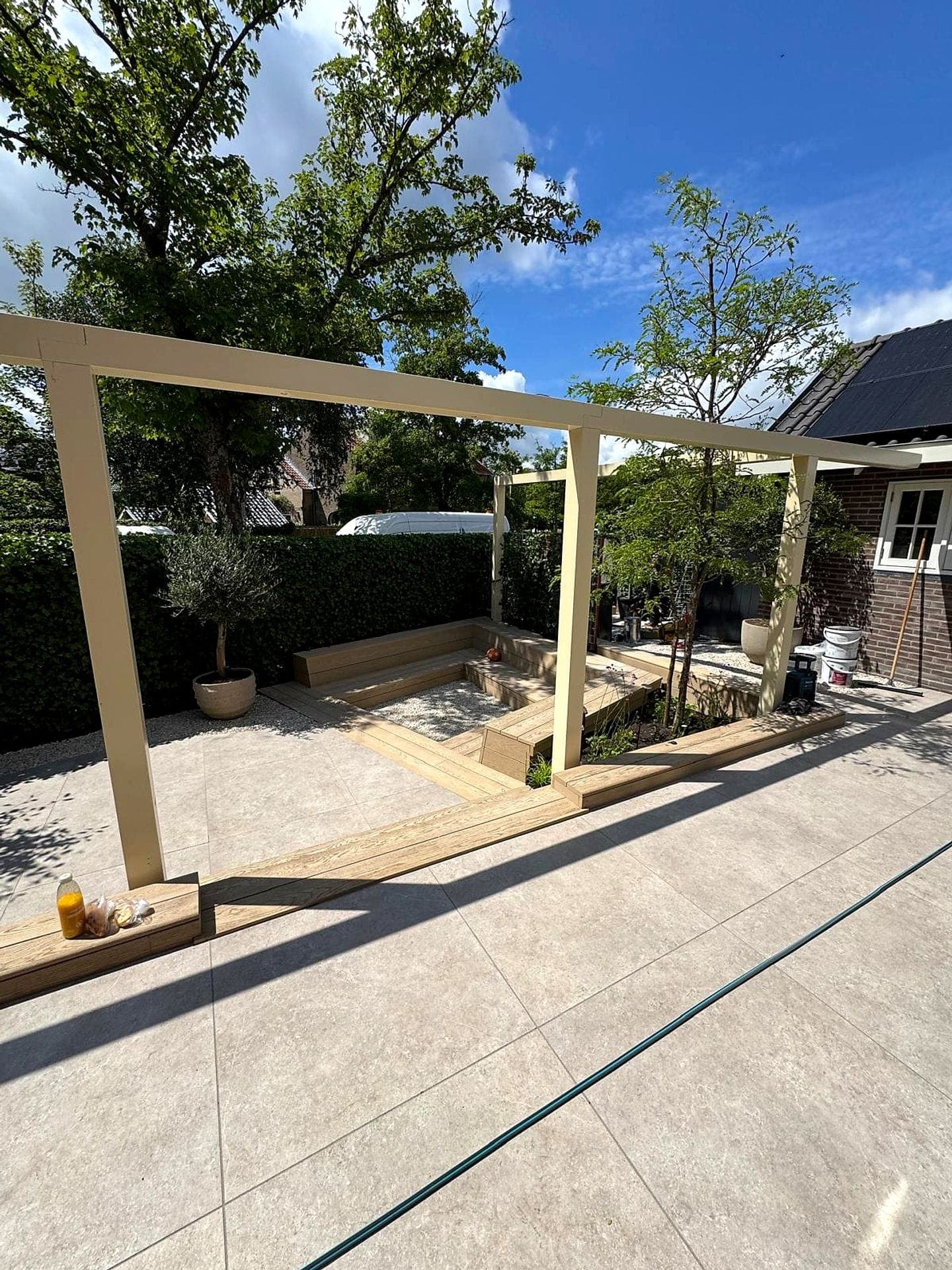 Houten pergola met verhoogde plantenbakken en olijfboom