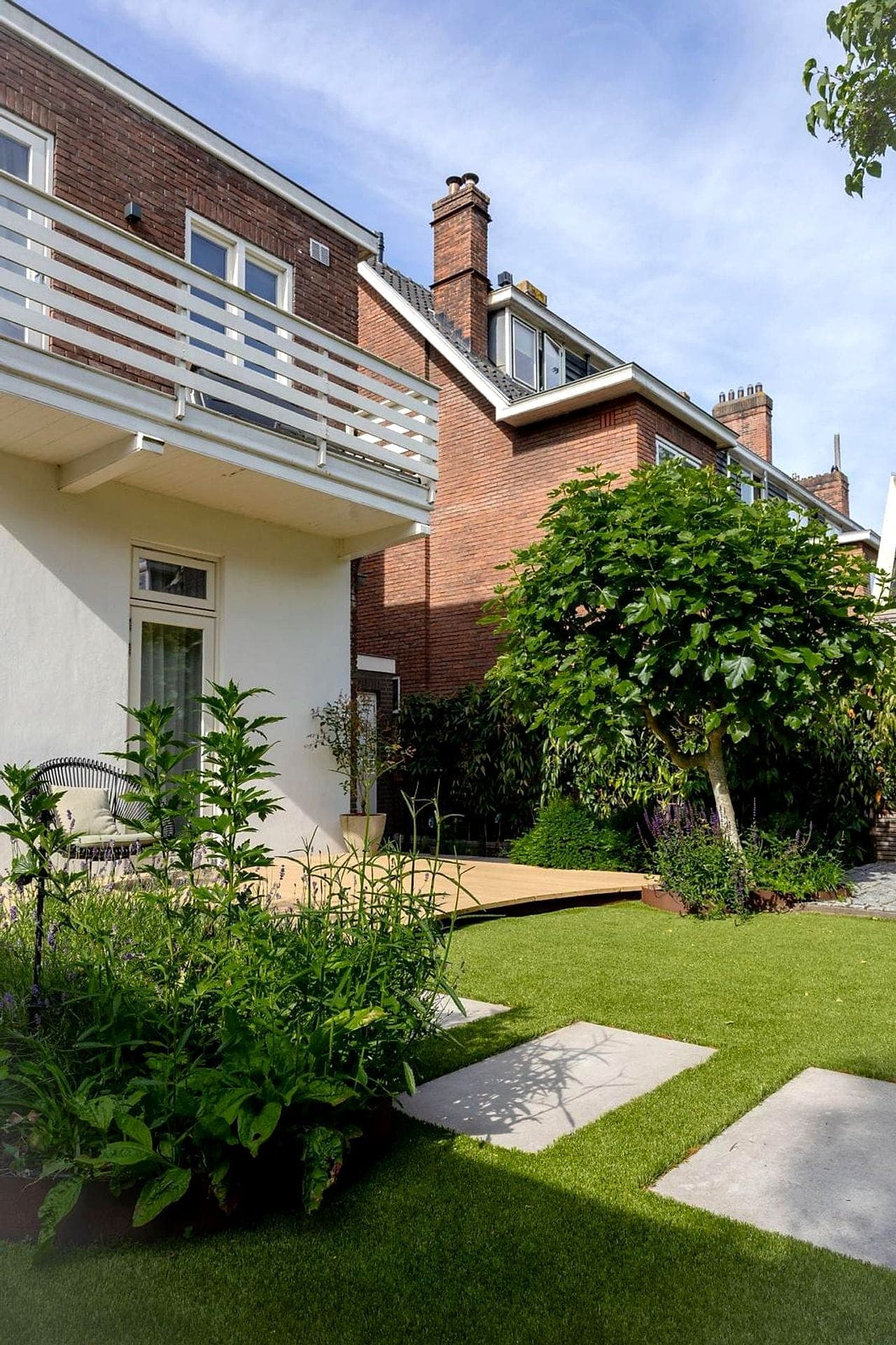 Witte woning met vlonder, gazon en boom
