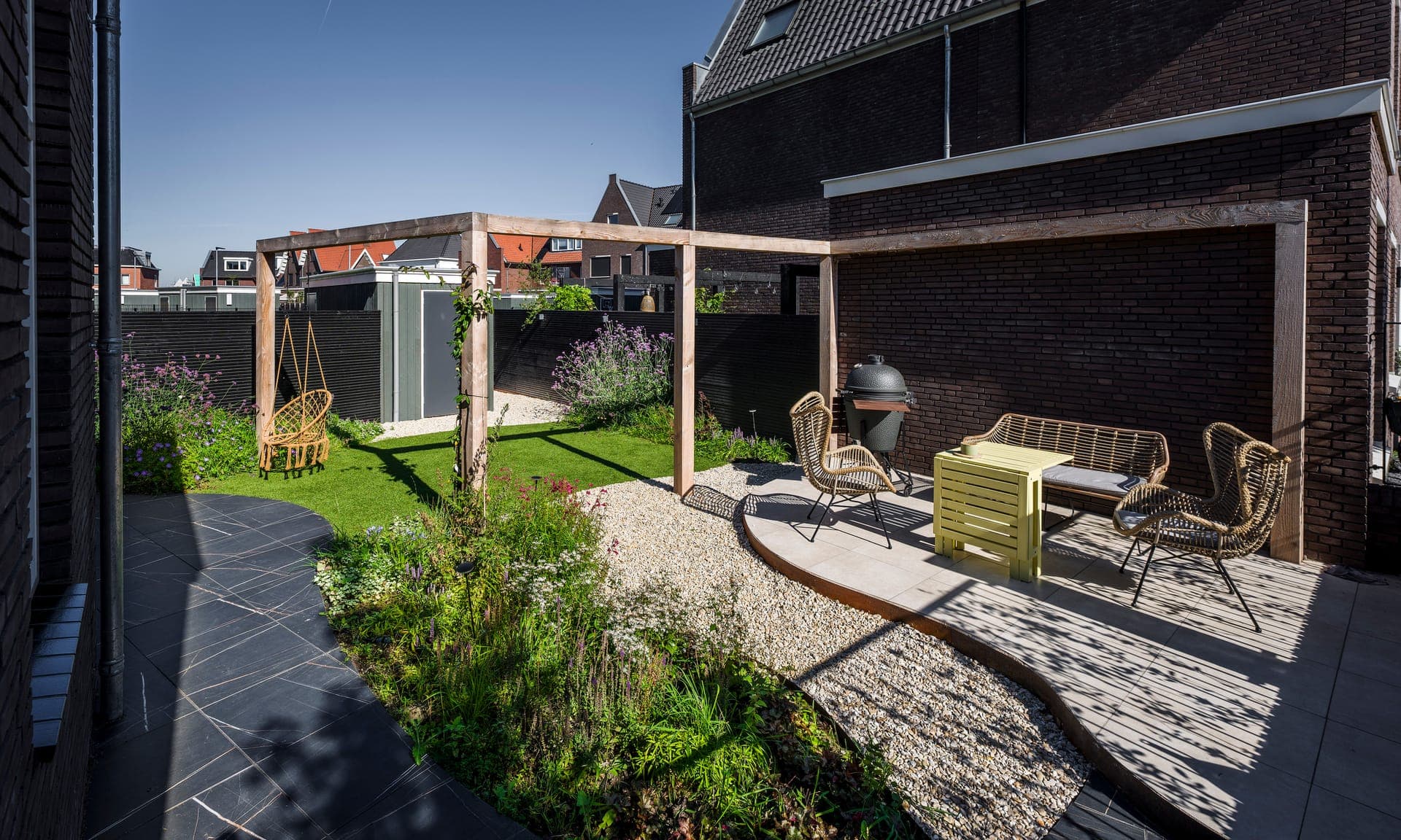 Houten pergola met hangstoelen, loungehoek en kamado