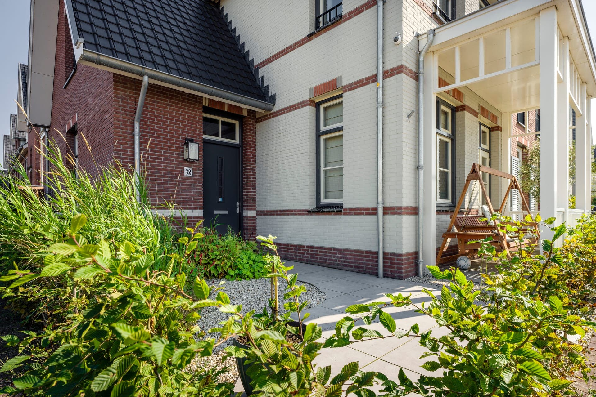 Entree met veranda, siergrassen en bestraat pad