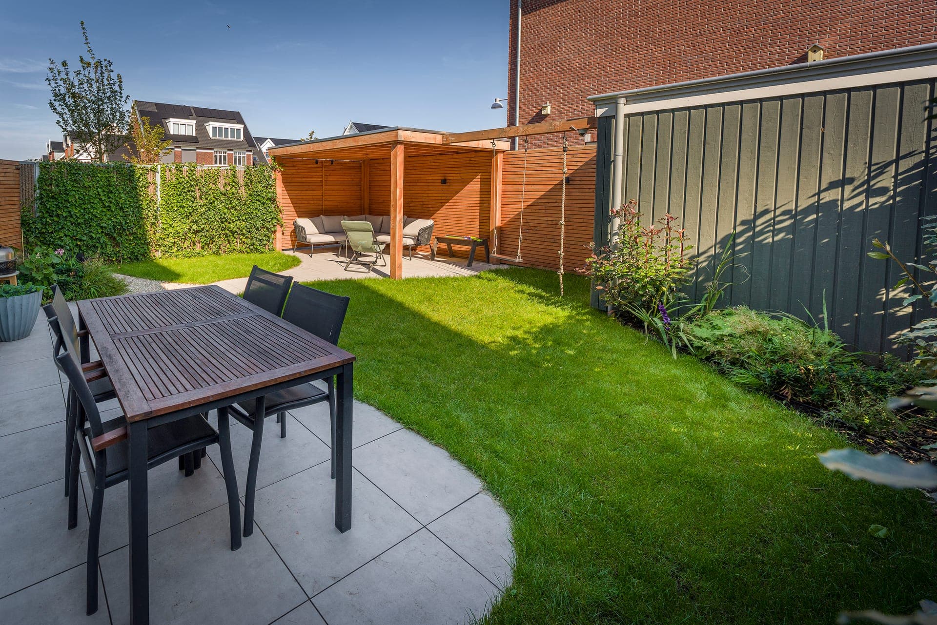 Terras met eettafel, gazon en houten pergola