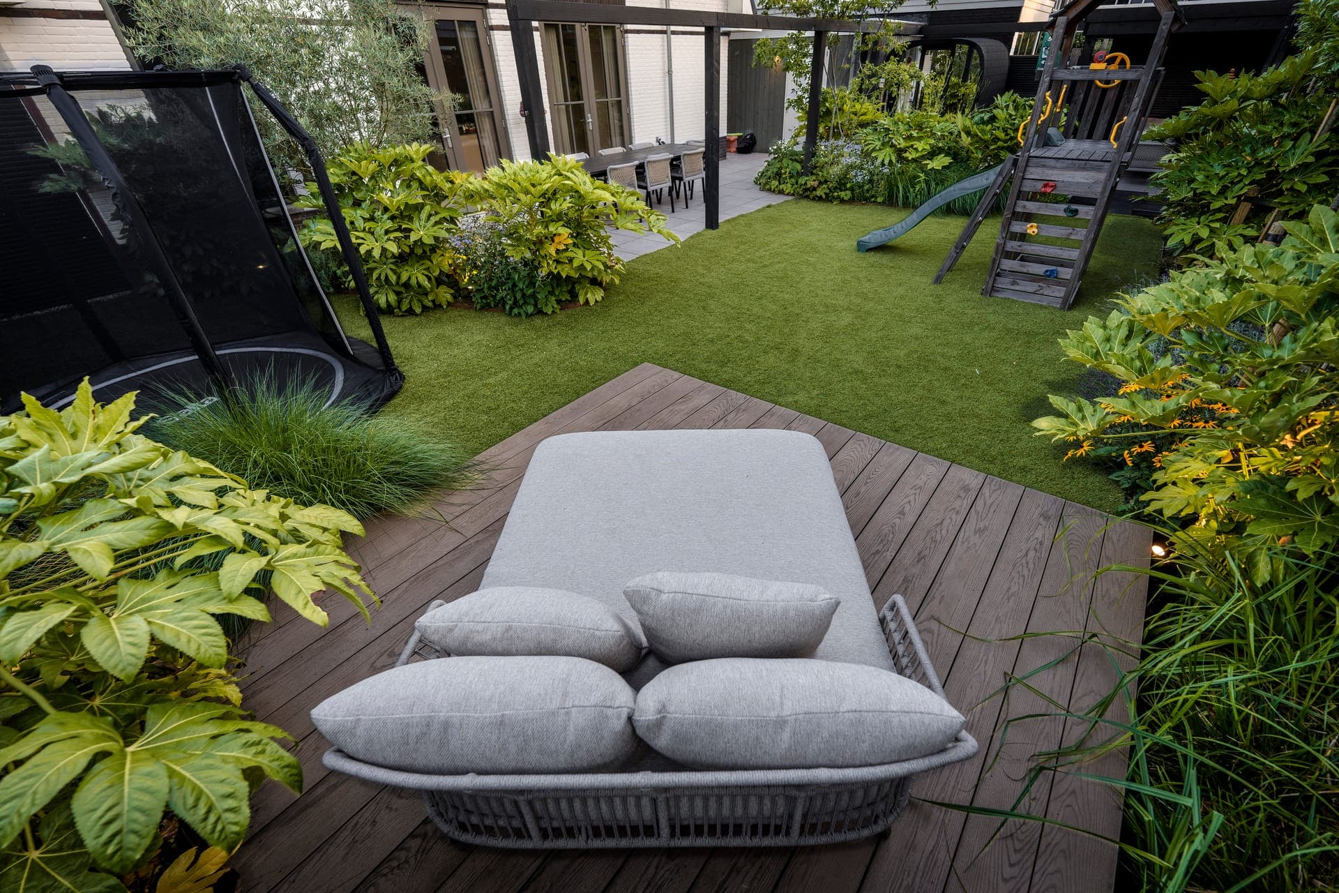 Daybed op de vlonder met trampoline en speeltoestel