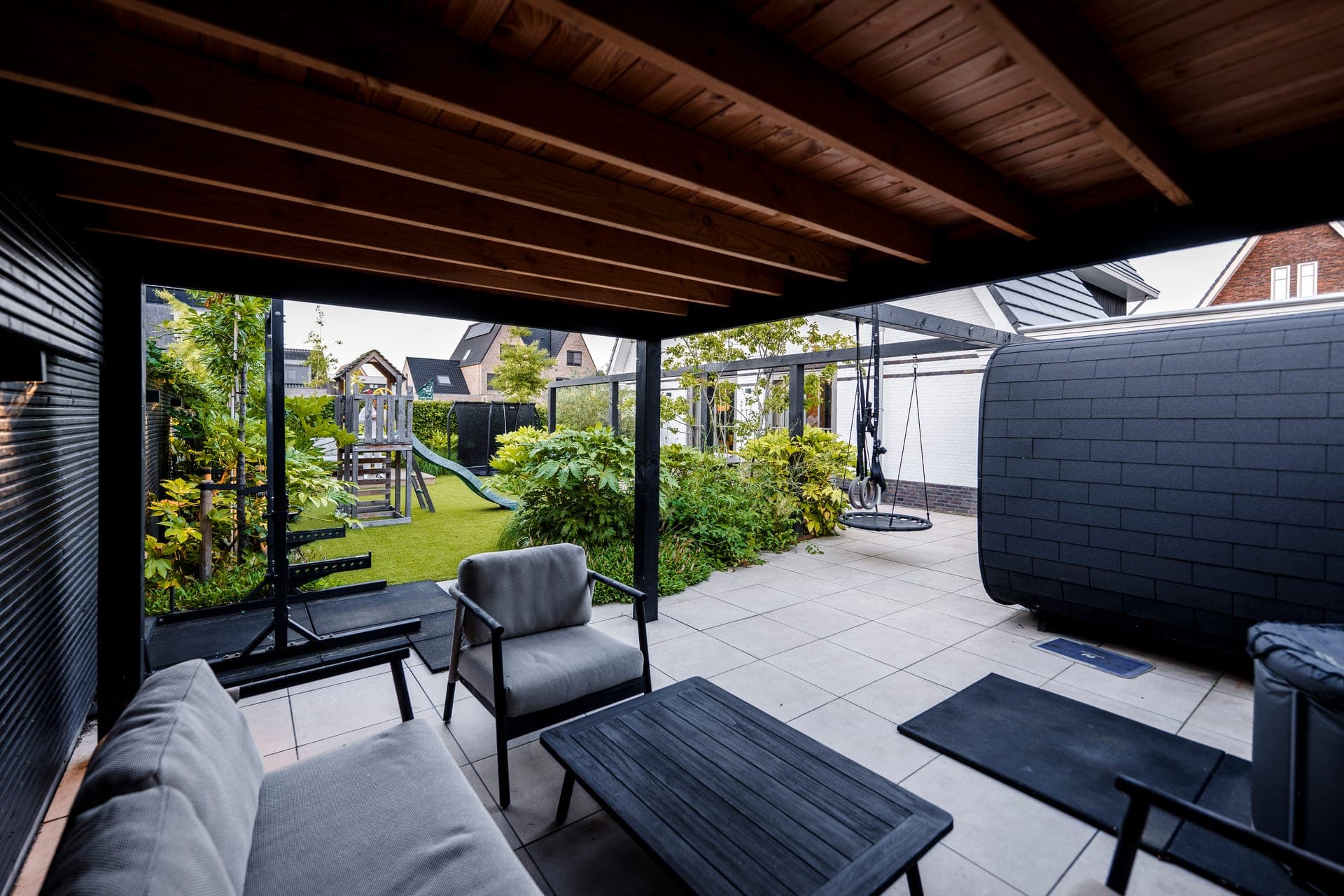 Zicht vanuit de overkapping op speeltuin en schommel