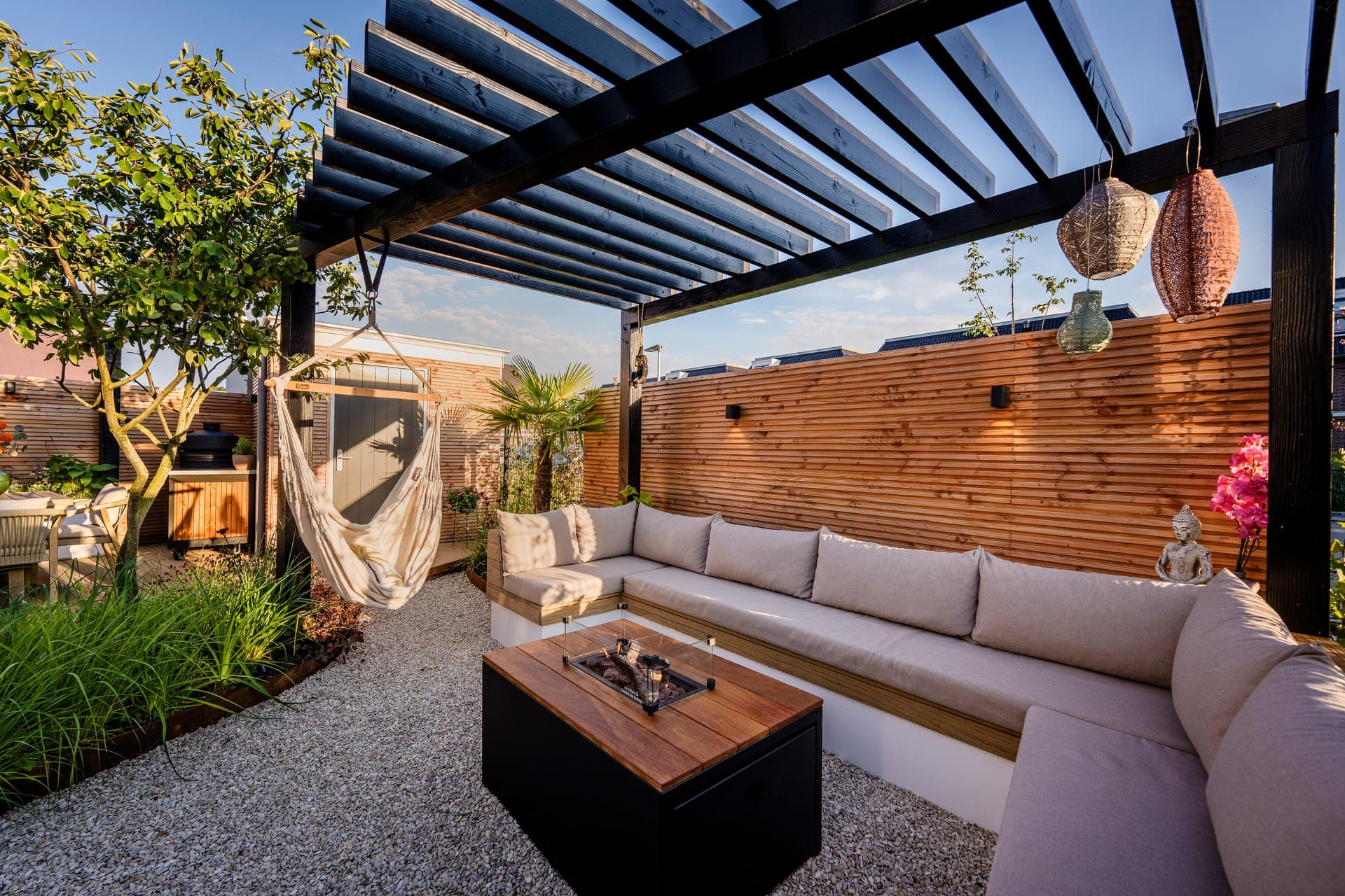 Pergola lounge met hangmat en vuurtafel bij gouden uur