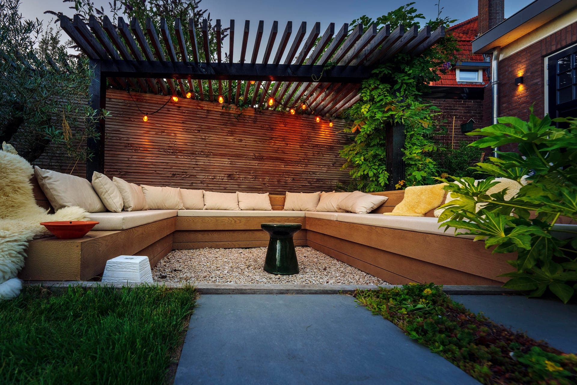 Verdiepte loungebank onder de pergola met lichtsnoer