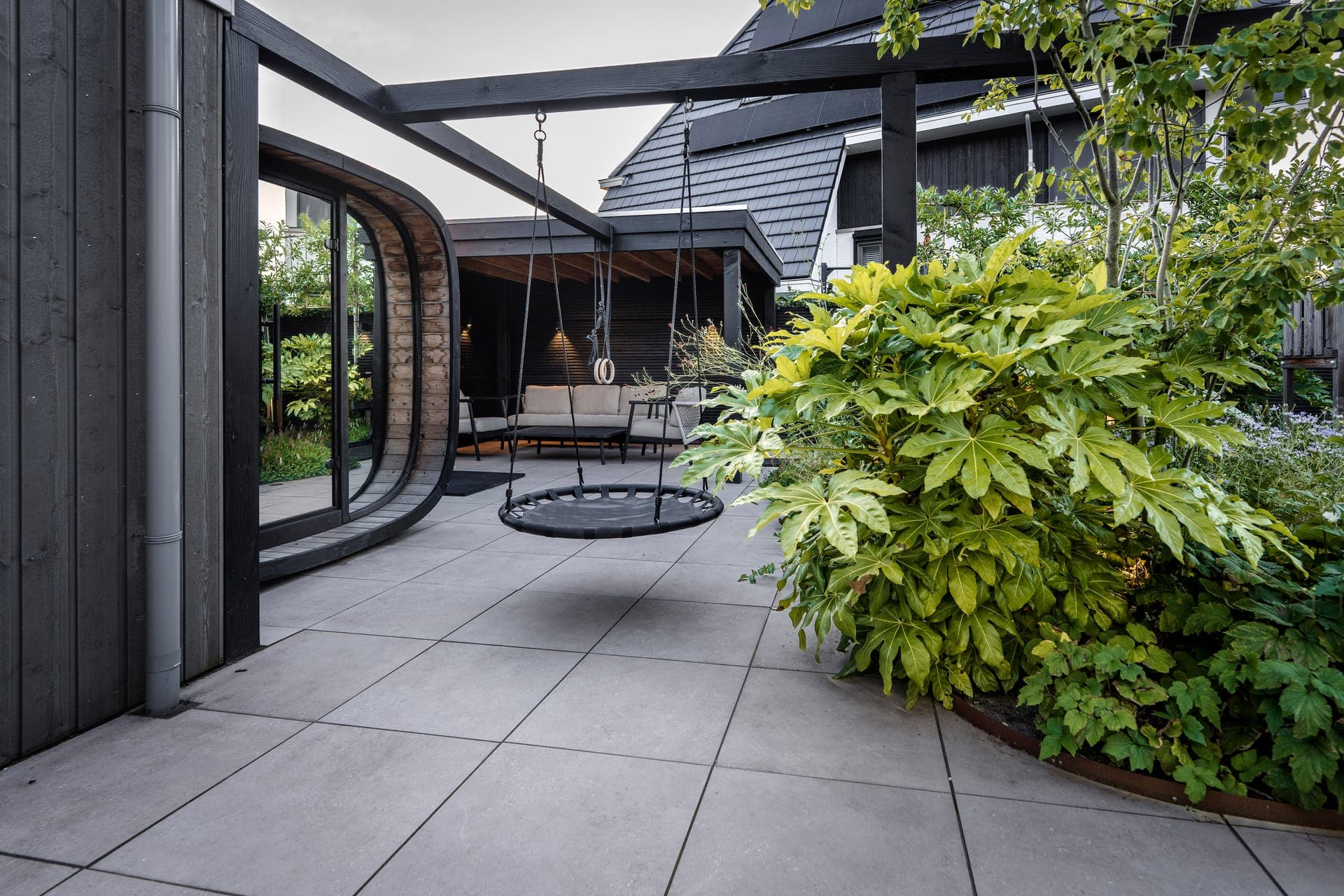 Modern zwart huis met gebogen pui en strak tegelterras