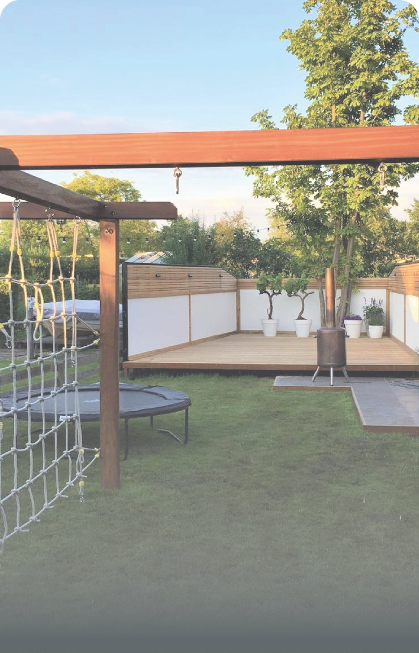 Een groene tuin met een houten platform, een schommel met net, een trampoline en planten in potten. Achtergrond is helderblau